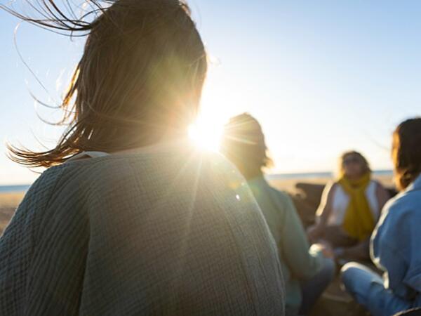 group of women sitting talking on beach on sunny windy day